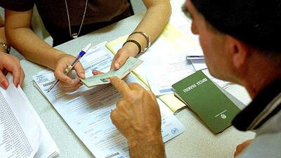 Person reviewing documents and passports at a registration desk.