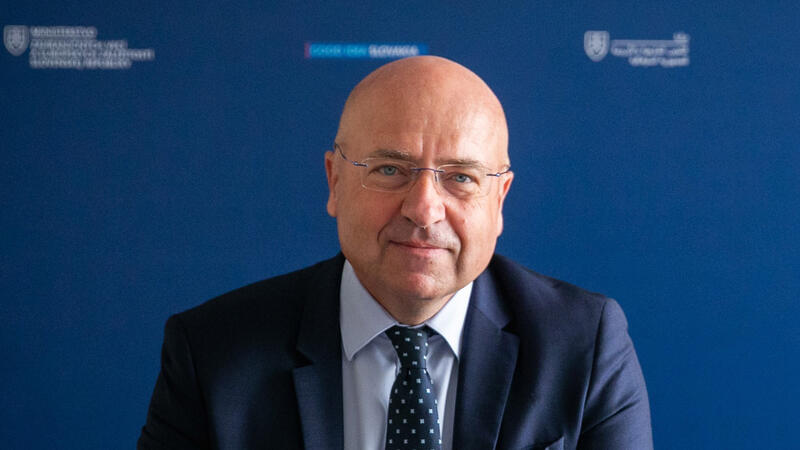 Ambassador Marcel Peško, Head of the OSCE Mission to Serbia, sitting against a blue backdrop with text logos.