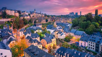 Colorful cityscape at sunset with charming houses, lush greenery, and a vibrant sky.