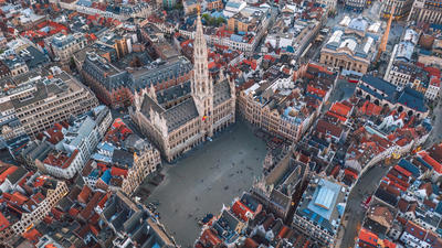 Aerial view of a historic city square surrounded by ornate buildings with a tall spire in the center.