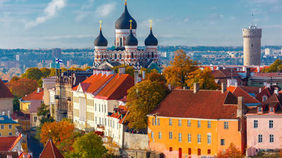 Old town with colorful rooftops, a cathedral with onion domes, and autumn trees under a clear sky.